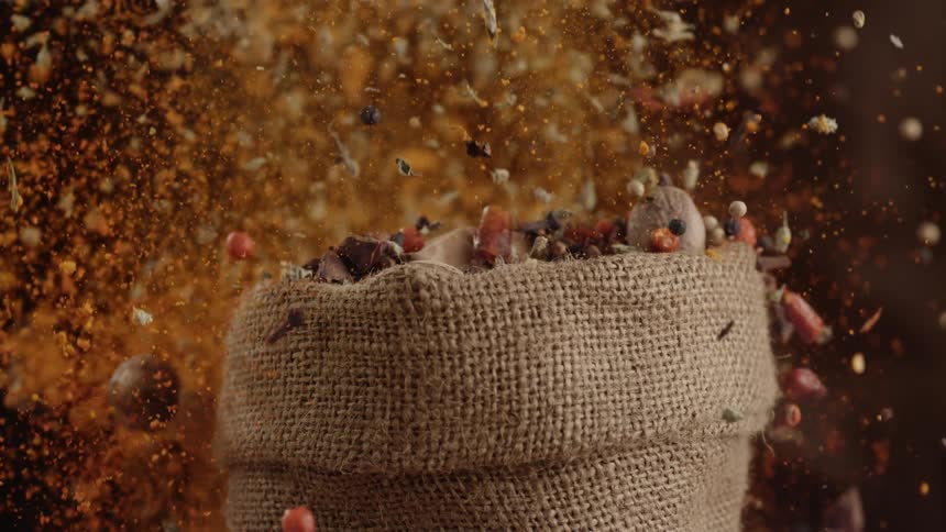 Spices and nuts explode from a burlap sack