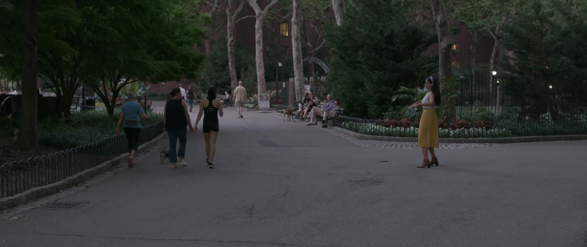 A woman dances playfully in the park as people walk