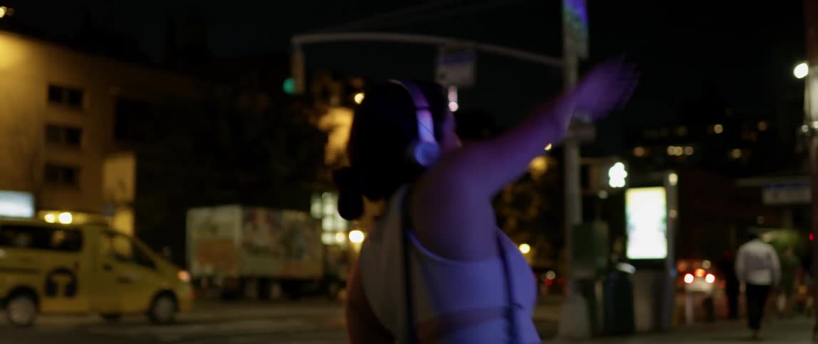 Woman listening to music and dancing in the street at night