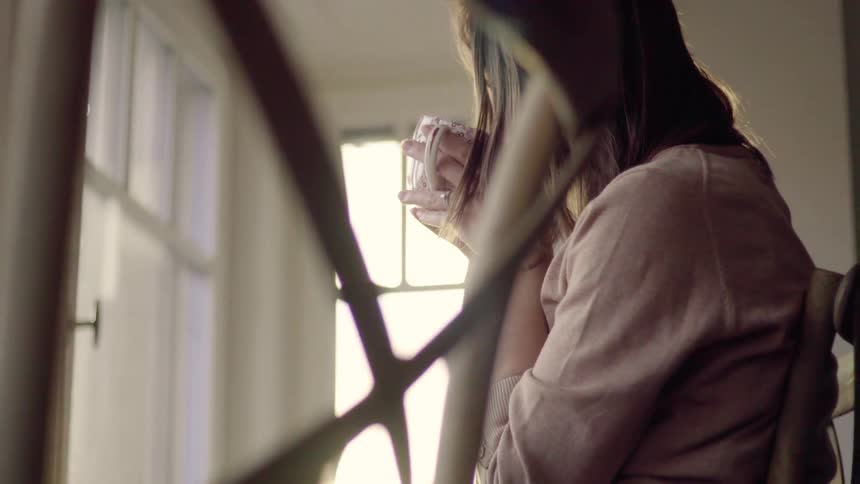 Woman sits on a chair sipping out of a mug