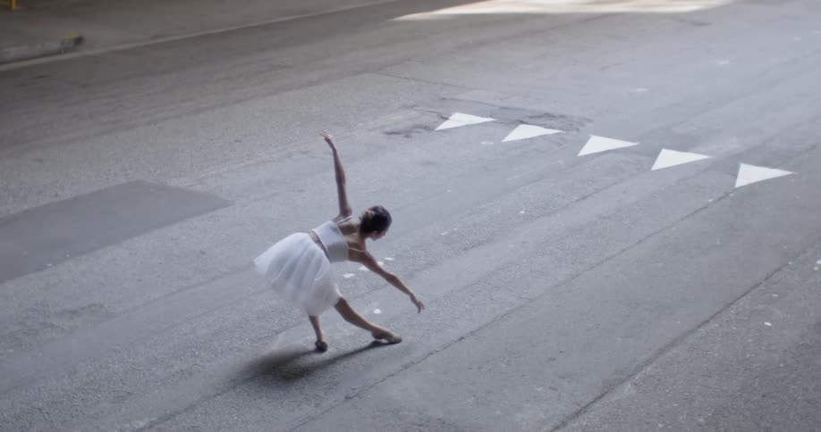 Woman dances ballet moves in the middle of a street