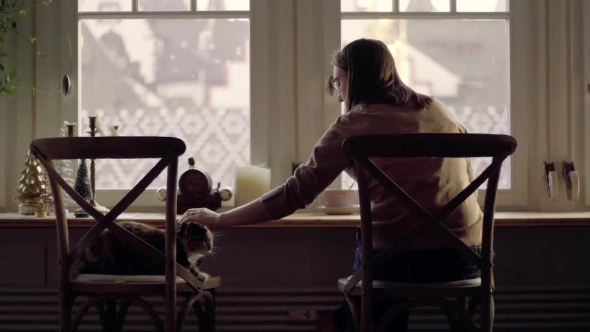 A woman pets a cat sitting in the chair