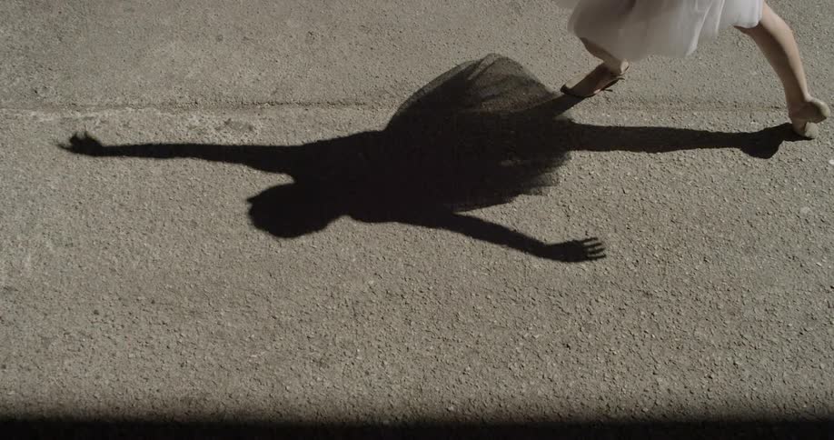 Shadow on road of ballerina dancing and posing on sunny day