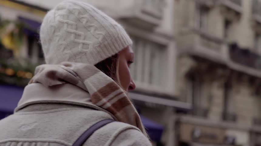 A woman is walking in a city in daylight in winter