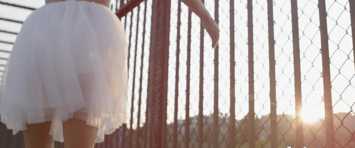 A woman in a white skirt walks by the railing and twirls