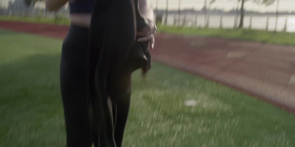 A jogger drinks from a water bottle and puts on her jacket