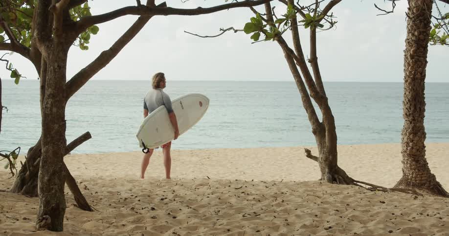 A man holds a surfboard on the beach