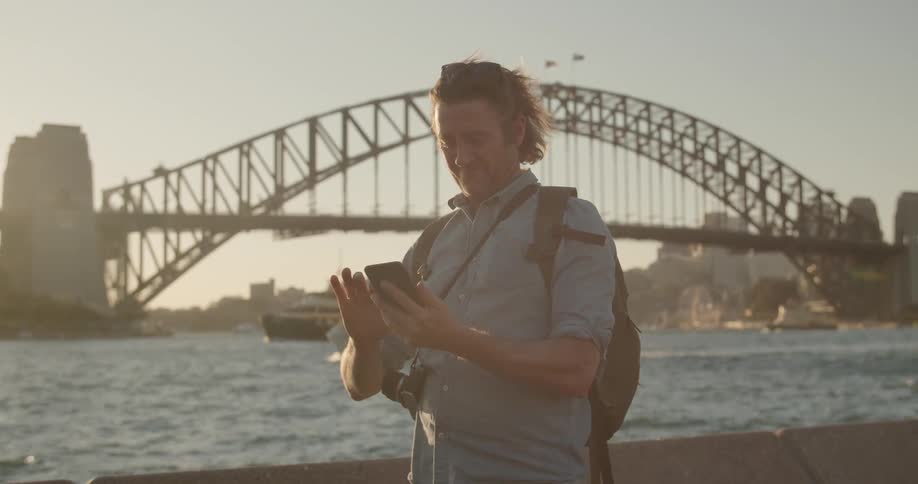 A man checks his phone by the water