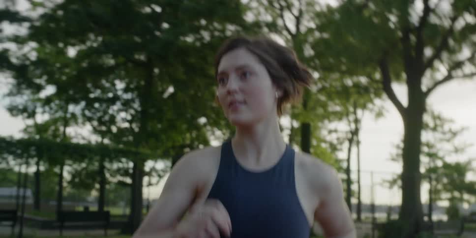Woman jogs on a track near trees
