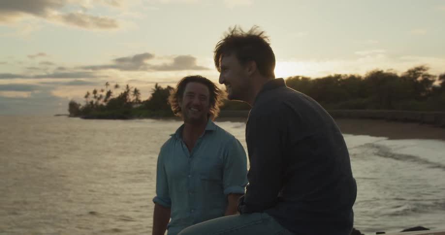 Two men laugh and talk by the water