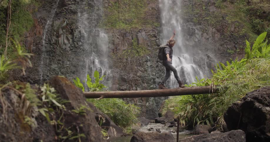 A man crosses a tree trunk bridge