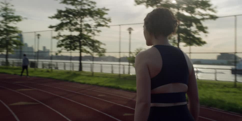 A woman jogs on a clay track by the water