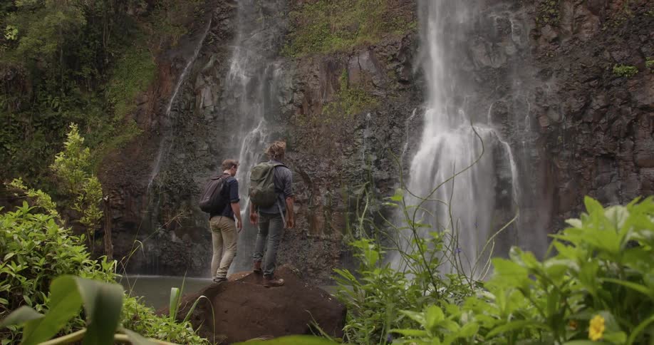 Two men stand by the waterfall