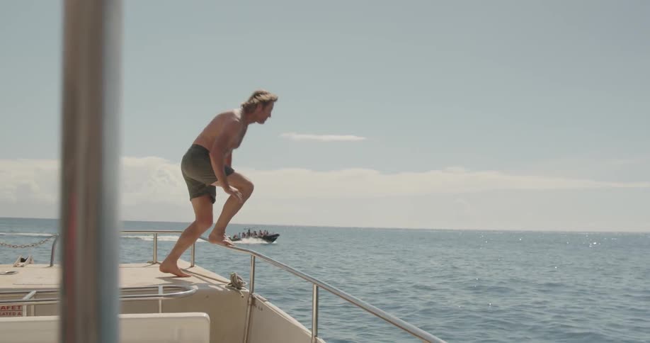 A man dives into the water from a boat