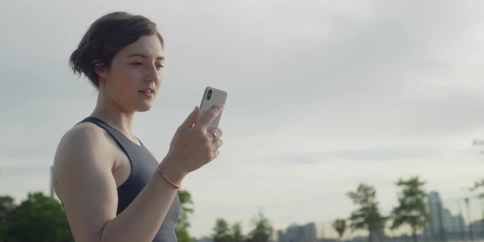 Woman stands on a track and looks at her phone
