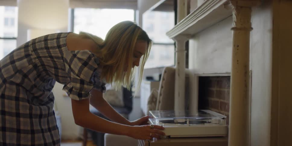 A woman adjusts a record player