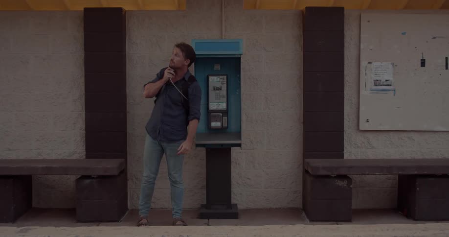 A man uses a pay phone outside
