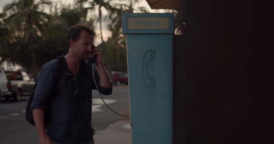 Man with backpack at pay phone