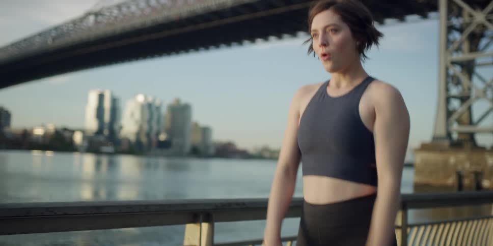 A woman stretches and jogs off by the water