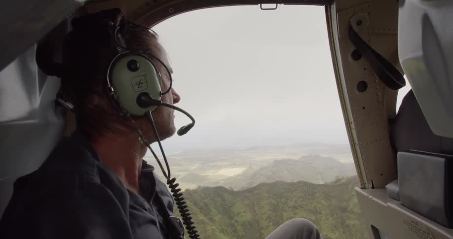 Man rides in a helicopter over mountains