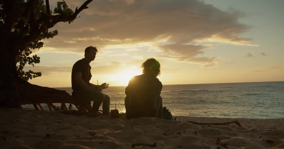 Two people talk on the beach at dawn