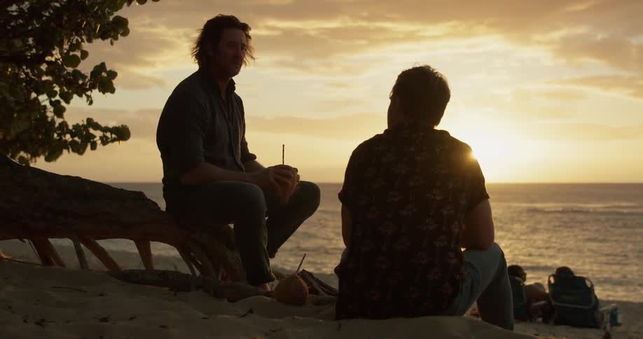 Two men drink together on the beach
