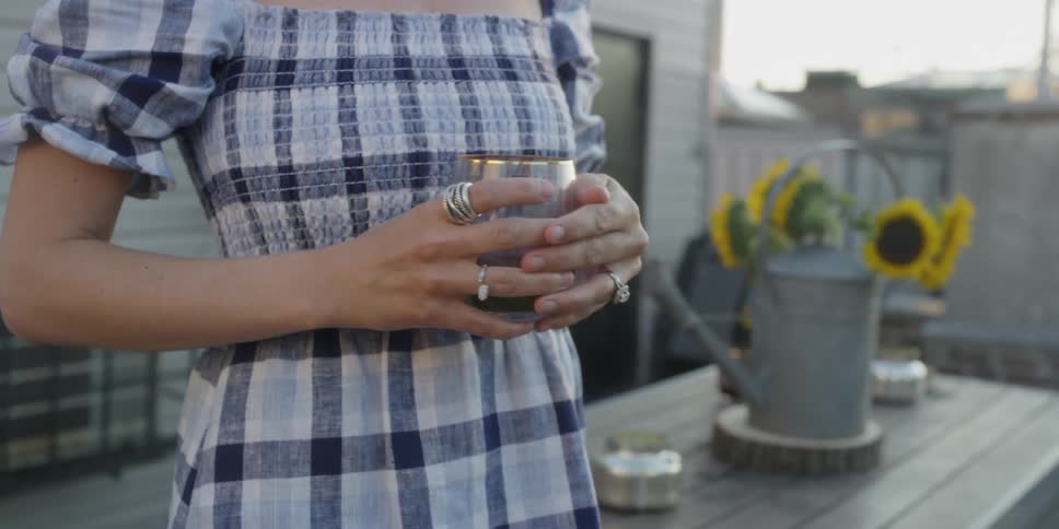 A woman holds a glass of red wine outside