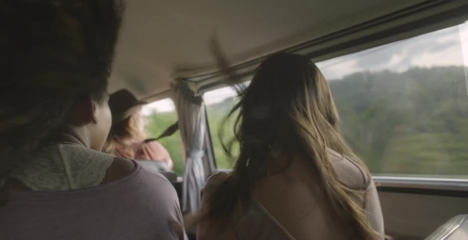 People riding in a vehicle with the windows down and the wind blowing through their hair