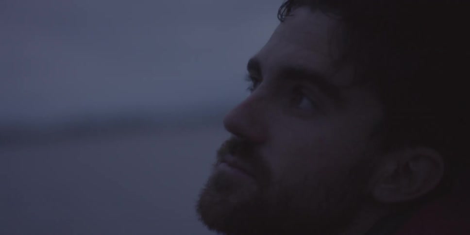 A man stares and blinks outdoors
