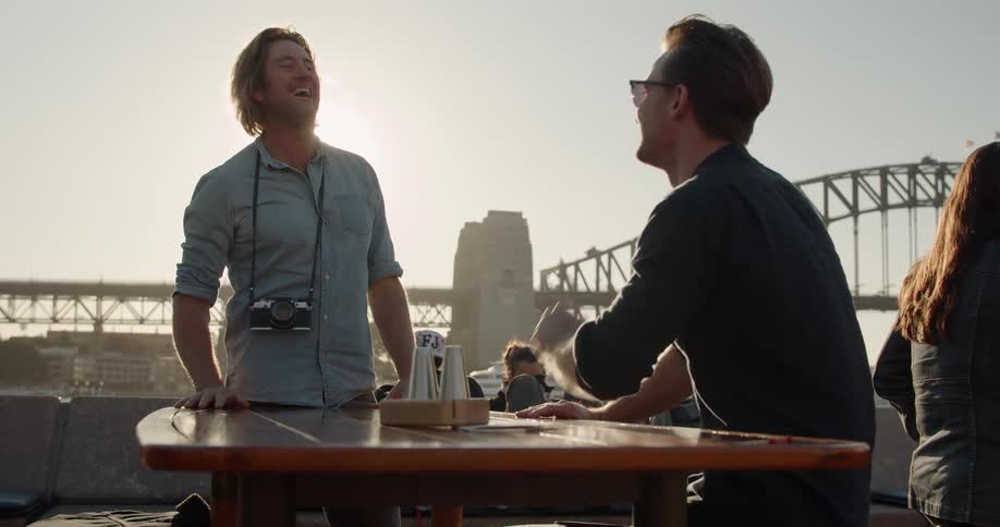 Two men talk at a table by the bridge