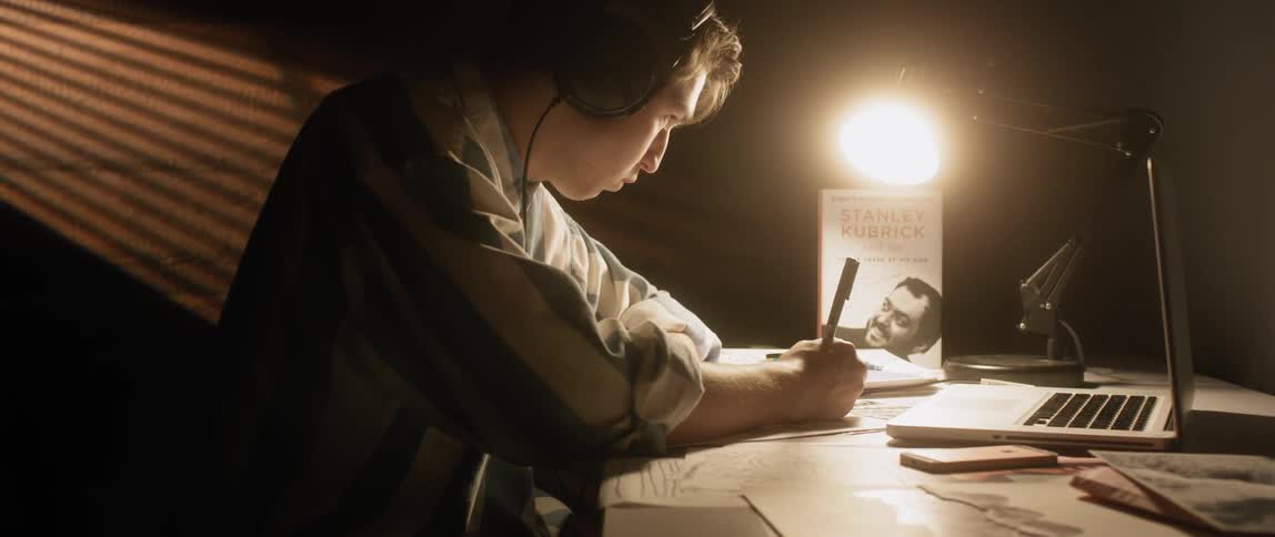 A man works at a desk while wearing headphones