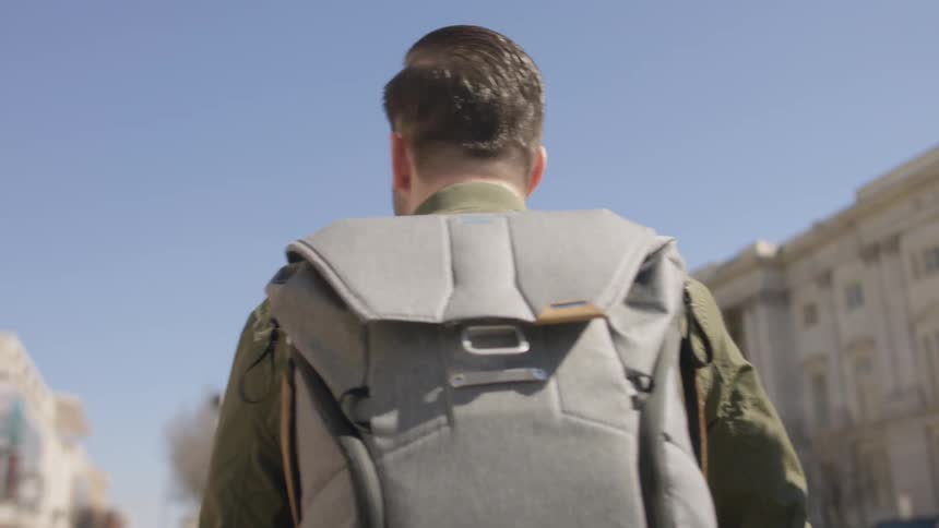 A man carries a backpack through the city