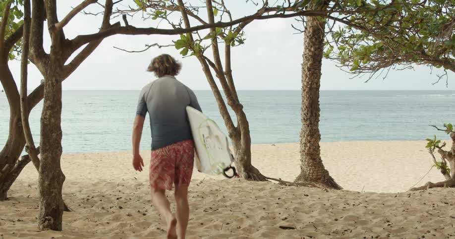 A man carries a surfboard on the beach