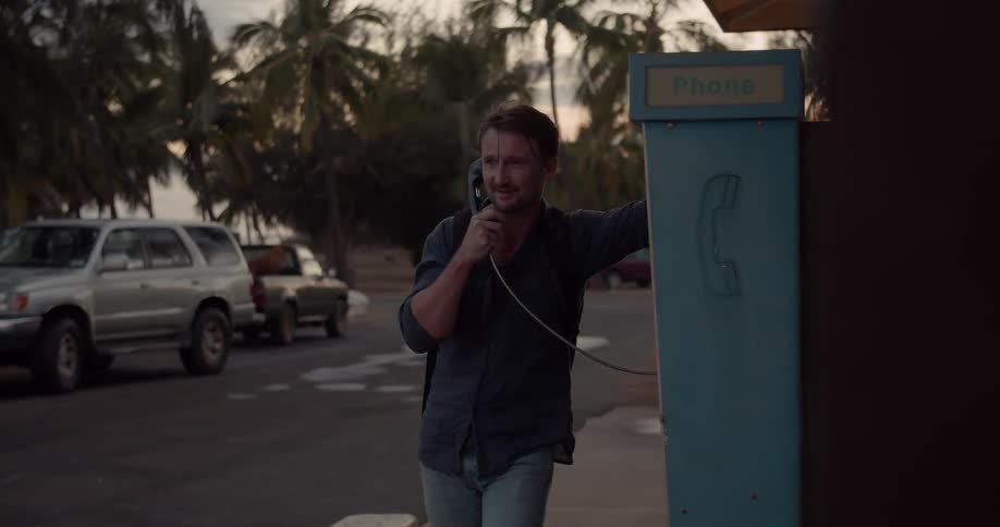 A man uses a pay phone outside
