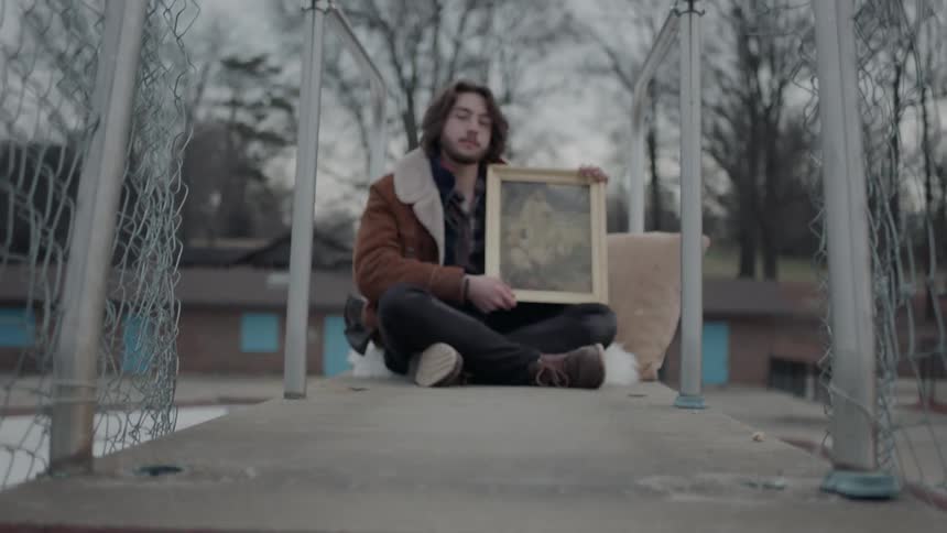 A man sits on the pool platform holding a picture
