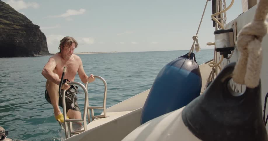 A man climbs up onto the boat