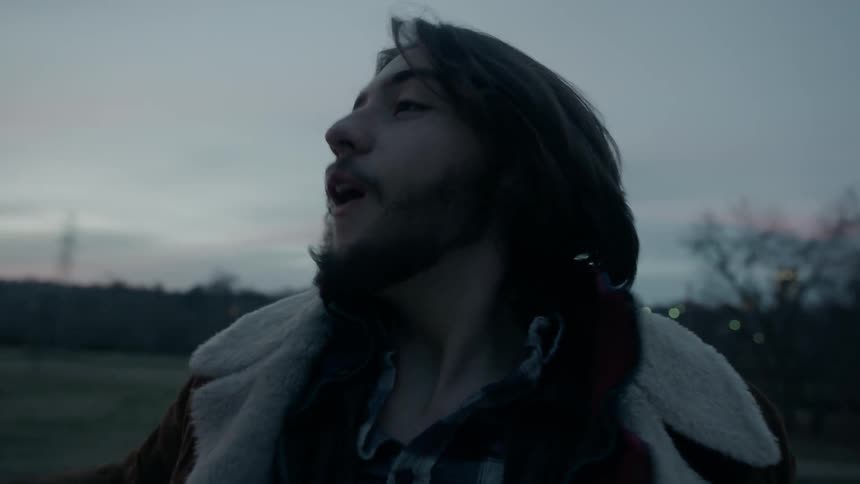 A man is shouting and cheering outside at dusk