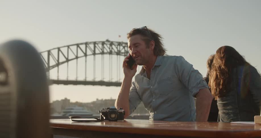 A man talks on his phone at a table outside