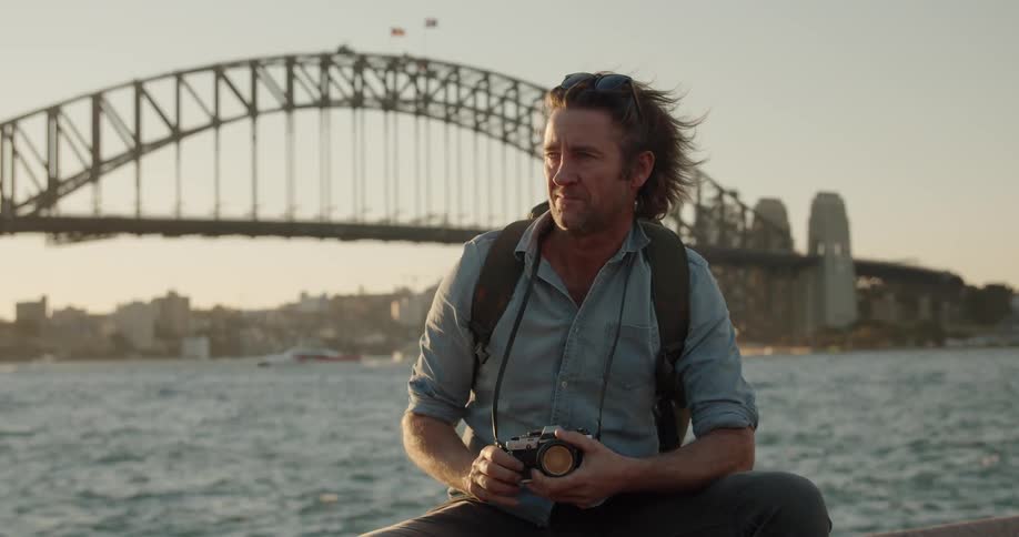 A man sits on the ledge with a camera