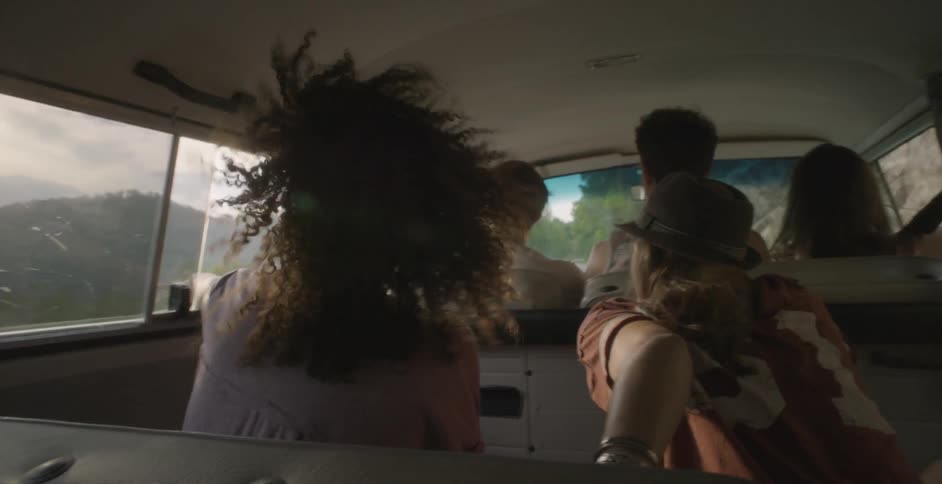 People riding in a vehicle through a mountainous area with the windows rolled down
