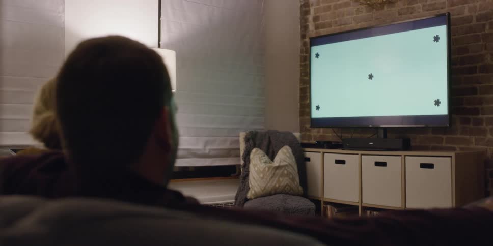 A man and woman watch tv at home