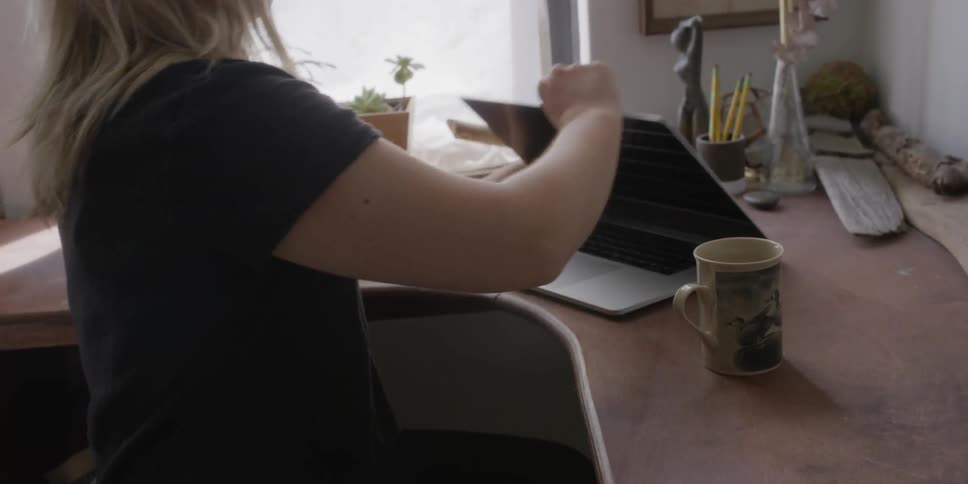 Woman playing a record at home while on laptop