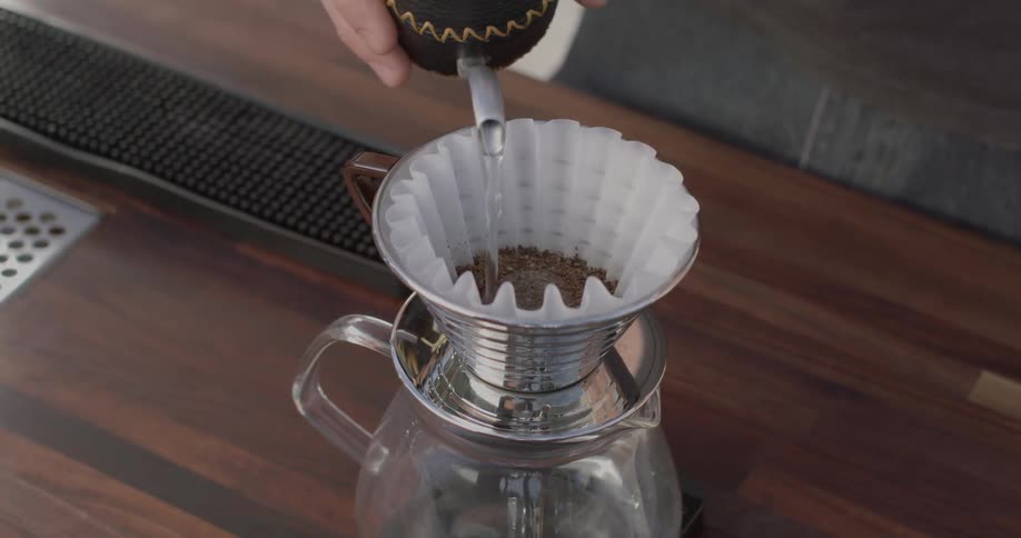 A person pours hot water over a filter full of coffee grounds