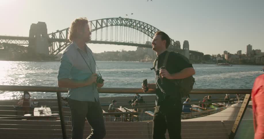 Two men talk together by the water
