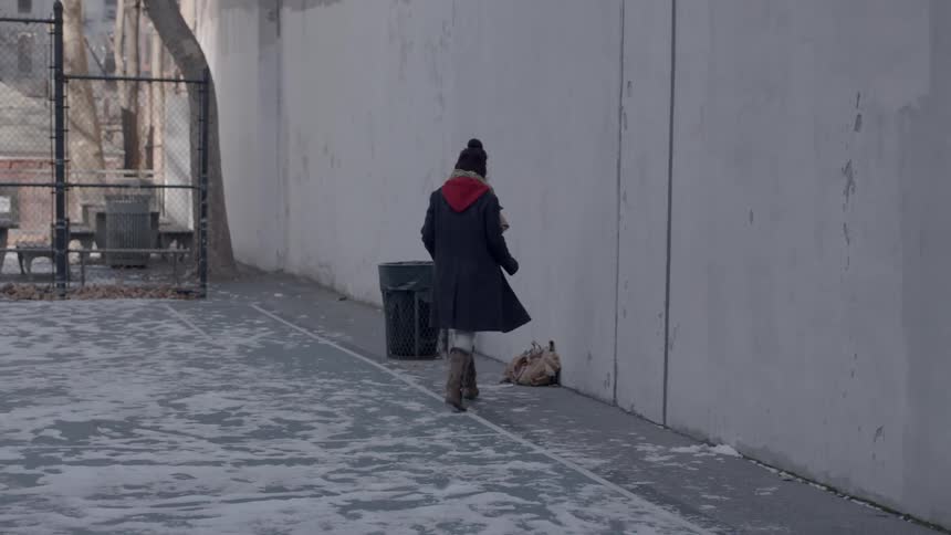A woman picks up a backpack outside in winter
