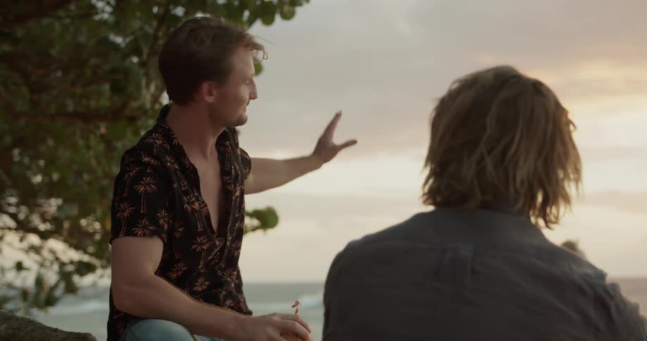 Two men drink together by the water