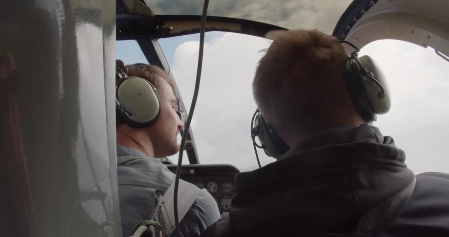 Two men are flying an airplane in the clouds