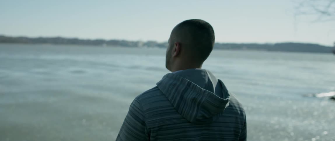 A man stands near the water taking in the view