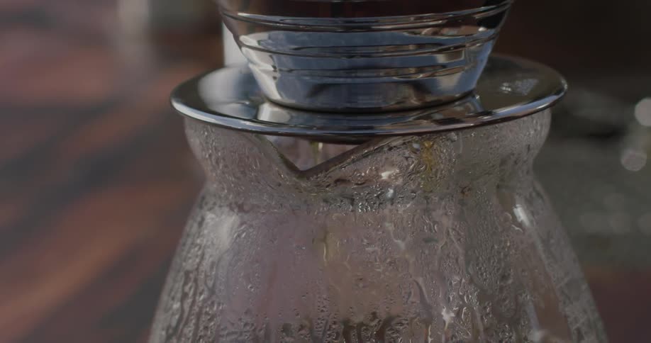 Tea is dripping into a carafe inside in daylight