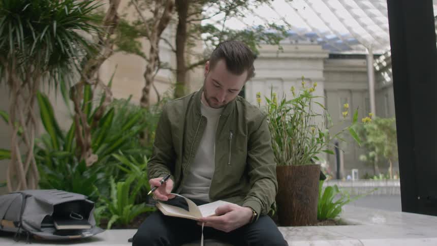 A man sits down flipping through his notebook